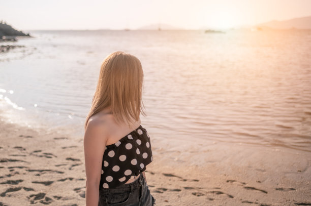 年轻女子穿着泳装在海滩上散步图片下载
