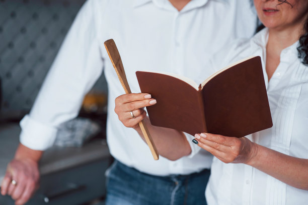 集中的照片。男人和他的妻子穿着白衬衫在厨房里用蔬菜做饭图片下载