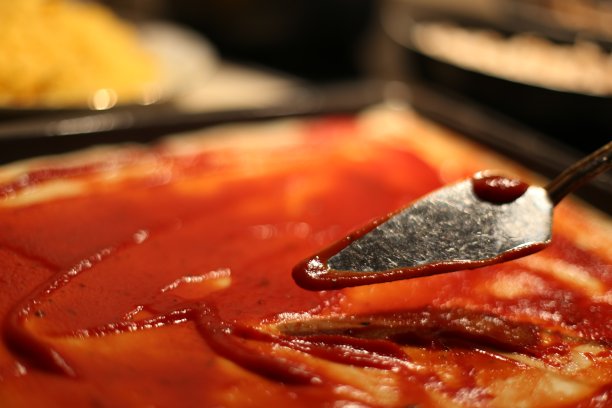 烹饪意大利比萨。生面团加番茄酱图片下载