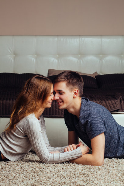 年轻相爱的夫妇躺在地板上拥抱和亲吻。男孩和女孩非常相爱图片下载