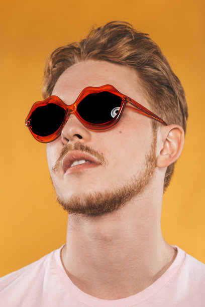 黄色背景上戴着唇型太阳镜的年轻人图片下载