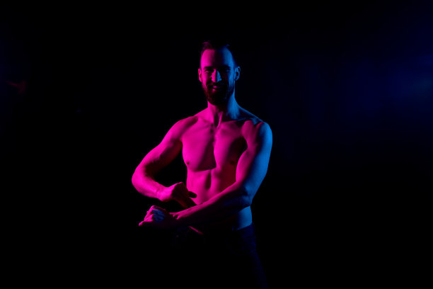 性感的赤膊男子与凝胶照明在黑色的背景图片下载