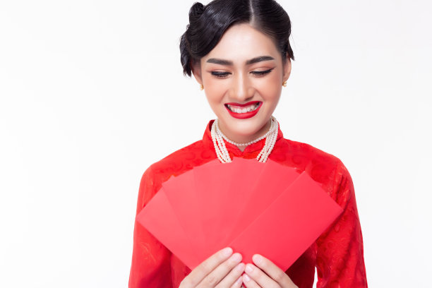 美丽的年轻女子拿着红包，看着笑脸红包在中国新年。漂亮的女人感到高兴，因为她从老板那里得到了很多钱或奖金。孤立的图片下载
