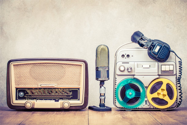 复古广播收音机，卷轴对卷轴磁带录音机大约60年代，麦克风和耳机在木桌子前面的混凝土墙背景。复古风格滤镜照片图片下载