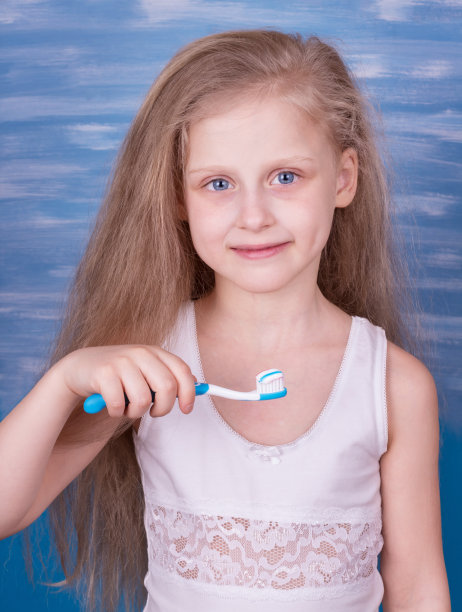 微笑的小女孩穿着白色t恤，牙刷和牙膏印在蓝色图片下载