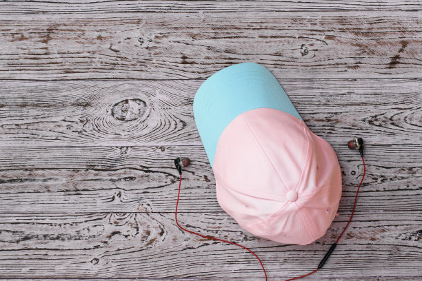 木桌上，粉色和绿松石色的帽子，戴着耳机。运动风格。极简主义。平的。图片下载