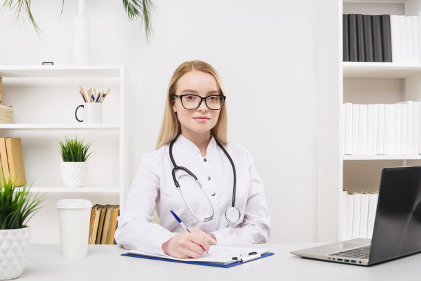 年轻美丽的女医生在医院工作快乐和微笑，坐在桌子上图片下载