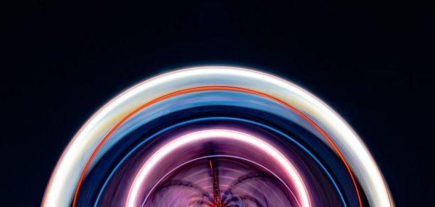 这是一个巨大的摩天轮在夜间长时间曝光后形成的非常美丽的半圆圆弧，它的轴快速旋转，被五颜六色的灯光照亮图片下载