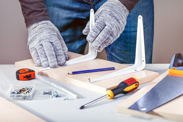 用手工工具组装家具的人。图片下载