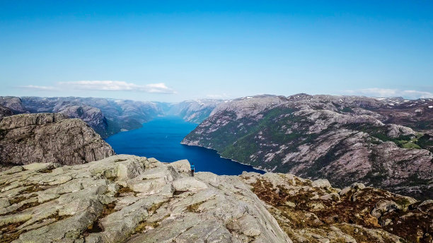 挪威——一个年轻人走在岩石之间，看到吕瑟峡湾图片下载