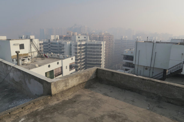 印度北方邦新德里装有卫星天线的公寓楼屋顶的图片，显示了早晨雾蒙蒙的天空污染的景象，被污染的雾蒙蒙的天空，德里污染的照片汽车尾气/工厂排放图片下载
