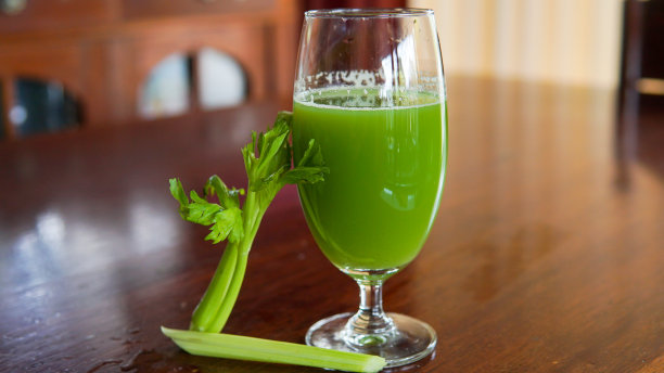 新鲜的绿色西芹汁玻璃上木棕色背景图片下载