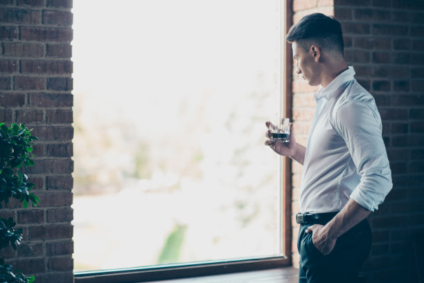近的侧面资料照片英俊的他他他沉思的思考手手臂威士忌饮料享受窗户的风景穿正式的服装服装规则衬衫长裤长裤站在室内现代的办公场所图片下载