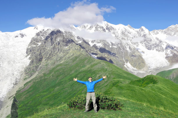 一个高举双手的人站在雪山的背景上图片下载