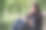 微笑的黑发女孩坐在长椅上的一个公园，喝着咖啡从一个纸杯和看在远处。她手里拿着一本软皮的书。图片下载