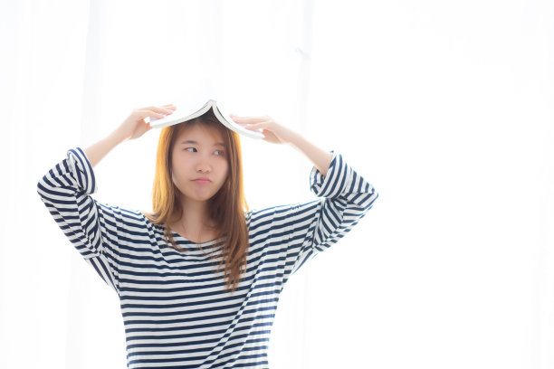 美丽的肖像年轻的亚洲女人站着看书学习考试与认真和压力在房间在家里，亚洲女孩拿着书的头与疲劳和紧张，教育理念。图片下载
