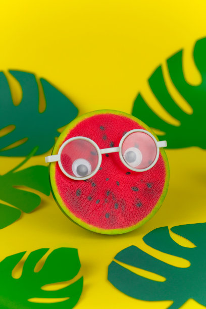 软绵绵的玩具西瓜在眼镜上的黄色背景图片下载