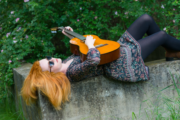 在大自然中弹奏吉他的年轻女子图片下载
