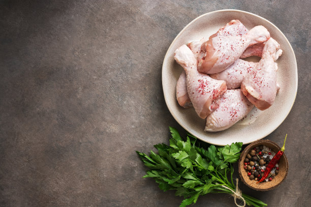 生鸡腿与香料和欧芹在黑暗的乡村背景。俯视图，复制空间。图片下载
