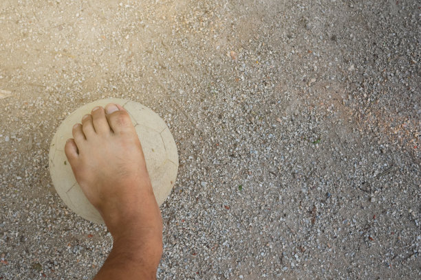 一个老球和一个正在踢足球的男孩的脚的特写照片图片下载