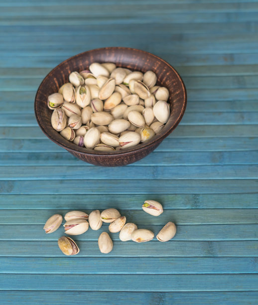 健康的食物背景图片近距离开心果。纹理上的白色灰色表顶视图。果仁，开心果，放在盘子里图片下载