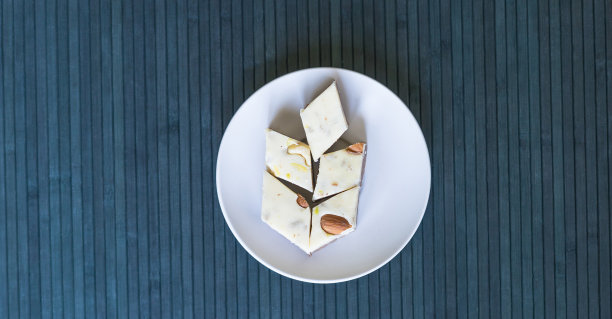 盘子里的东方甜点哈瓦，配开心果、杏仁、腰果、花生、核桃。图片。健康食品。伊朗甜点特写，在Machane Yehuda市场很受欢迎，土耳其软糖。隔离在背景上图片下载