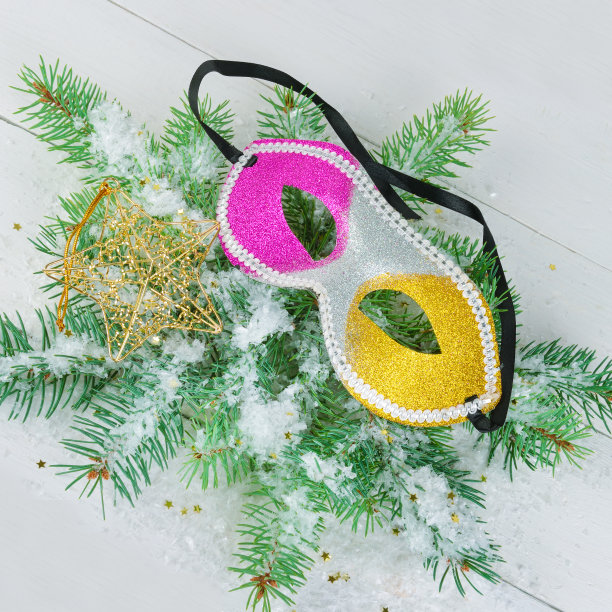 圣诞节或新年装饰品。一个由冷杉树枝组成的花环，一个面具和一个装饰星在白色的木制背景上。图片下载