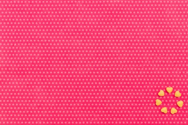 在纺织品背景上的一个马克杯形式的黄色糖果心。图片下载