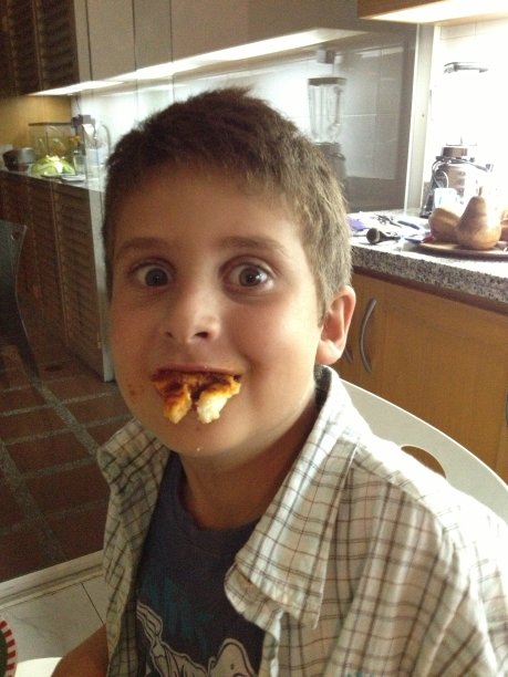 拿披萨做鬼脸的淘气小孩图片下载