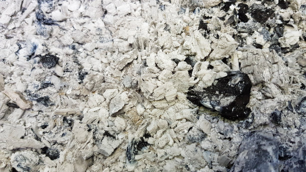 深浅不一的灰色背景与大块黑色烧焦木炭。烧焦的柴火纹理后，木柴篝火熄灭。壁炉的底部特写。灰色调的煤纹理。图片下载