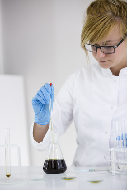 快乐的女科学家在实验室中研究从大麻植物中提取的CBD油。她戴着眼镜，使用玻璃滴管和玻璃管。医疗保健药房从药用大麻。图片下载