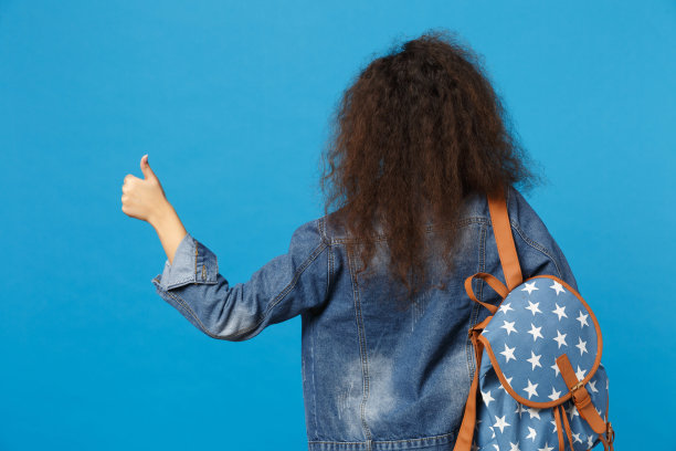 年轻的非洲裔美国女孩十几岁的学生在牛仔衣服，背包里的书孤立在蓝色的墙壁背景工作室肖像。中学教育中的大学学院观念。模拟拷贝空间图片下载