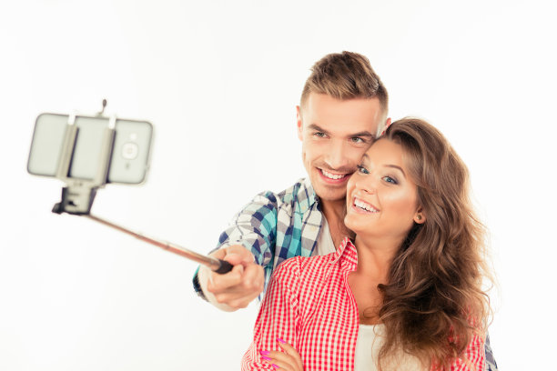 幸福可爱的情侣在爱与自拍杆自拍照片图片下载