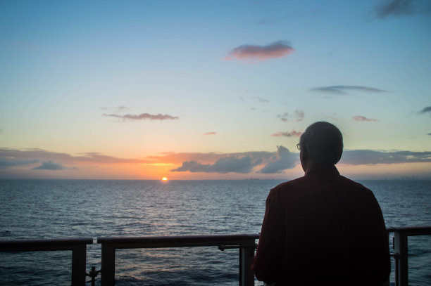 在海上的游轮上，一个人看着阴沉的天空日落图片下载