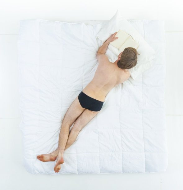 性感的男人在床上穿着内衣，看书图片下载