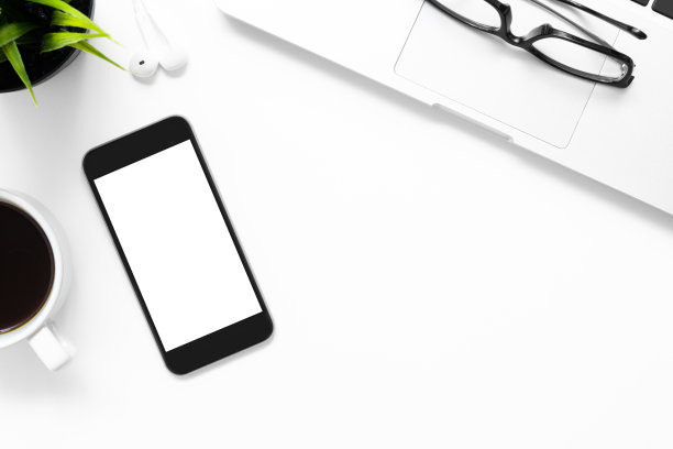 白色办公桌桌子与智能手机与空白屏幕和其他办公用品。顶视图与复制空间，平放。图片下载