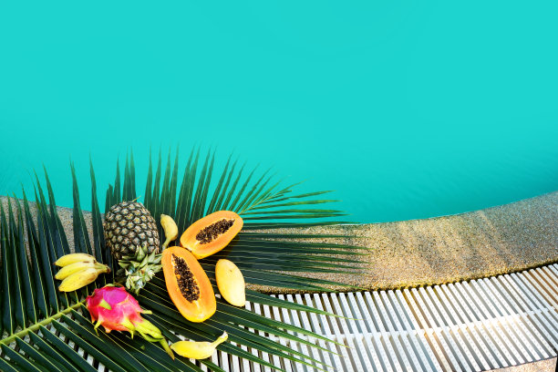 池边的棕榈叶上躺着许多热带水果图片下载