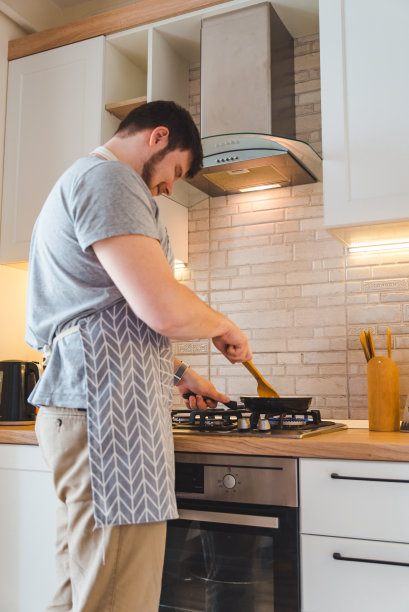 在厨房里煎锅的男人。烹饪概念图片下载