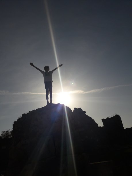 旅行者男孩享受着站在岩石上的自由之美图片下载
