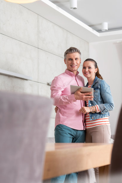 微笑的情侣手拿平板电脑站在公寓里的照片图片下载