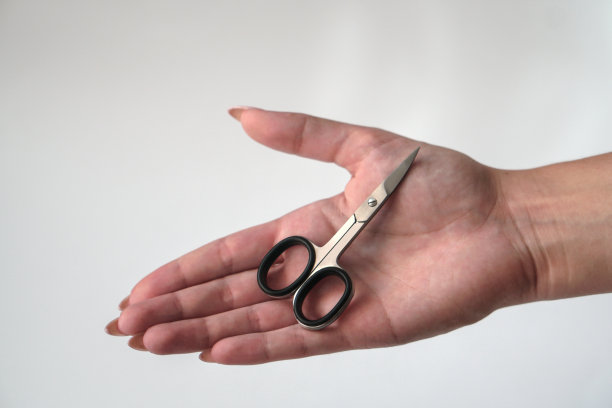 一个小女孩手上拿着修指甲的剪刀。女性美容和身体护理。库存图片图片下载