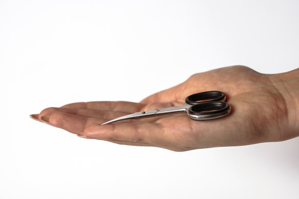 一个小女孩手上拿着修指甲的剪刀。女性美容和身体护理。库存图片图片下载