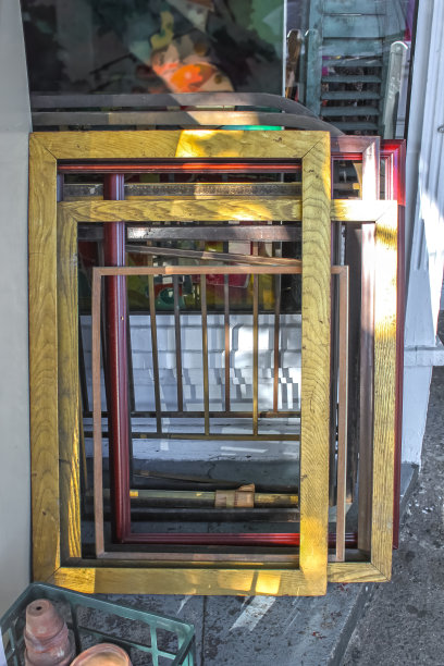 各种各样的空画框堆放在一堵旧墙上，靠着一堆其他的破烂图片下载