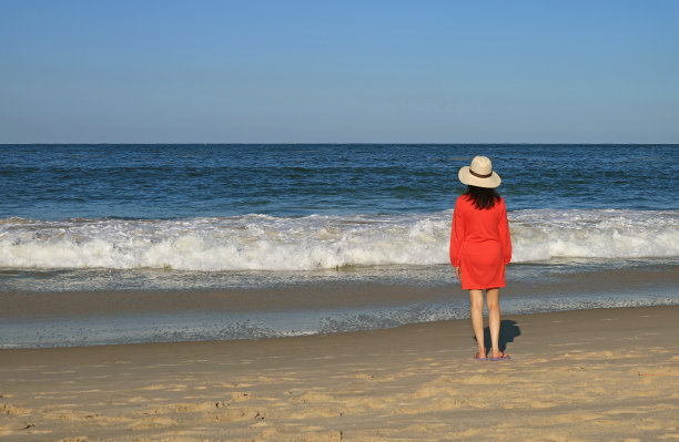 女人看着海滩上溅起的浪花图片下载