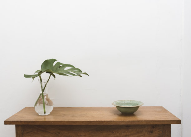 玻璃花瓶和橡木桌子上的绿碗里的绿叶图片下载