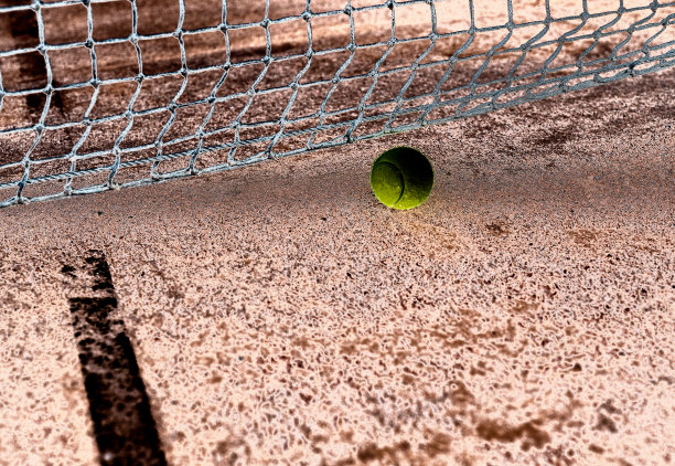 黄色网球在红土球场上带网的负面形象图片下载