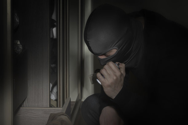 小偷戴着面具在房间里拿着手电筒寻找金钱和贵重物品图片下载