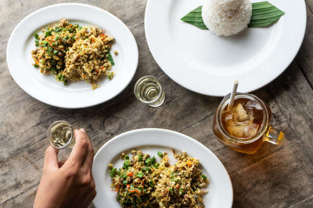 巴厘的传统食物叫拉瓦尔。拉瓦尔是切碎的肉与蔬菜、长豆角和香料混合，然后搅拌均匀。用米饭和冰茶吃。放在木桌上，手放在上面图片下载