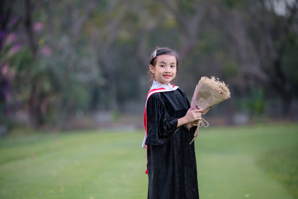 亚洲可爱的女孩毕业。女孩微笑着穿上幼儿园毕业服图片下载