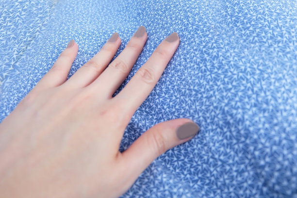 美丽的棕色指甲。化妆品女人手指甲。女人的手与棕色抛光剂孤立在蓝色柔和的织物背景伟大的任何使用。图片下载